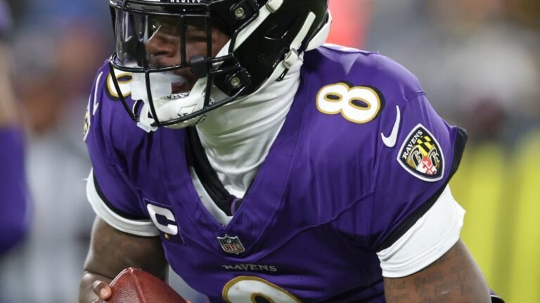 a football player in a purple uniform holding a football